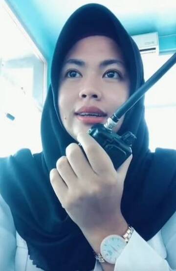 Foto Wanita Berjilbab Sedang Menggunakan Radio HT (Handy Talkie) Walkie Talkie Jarak Jauh